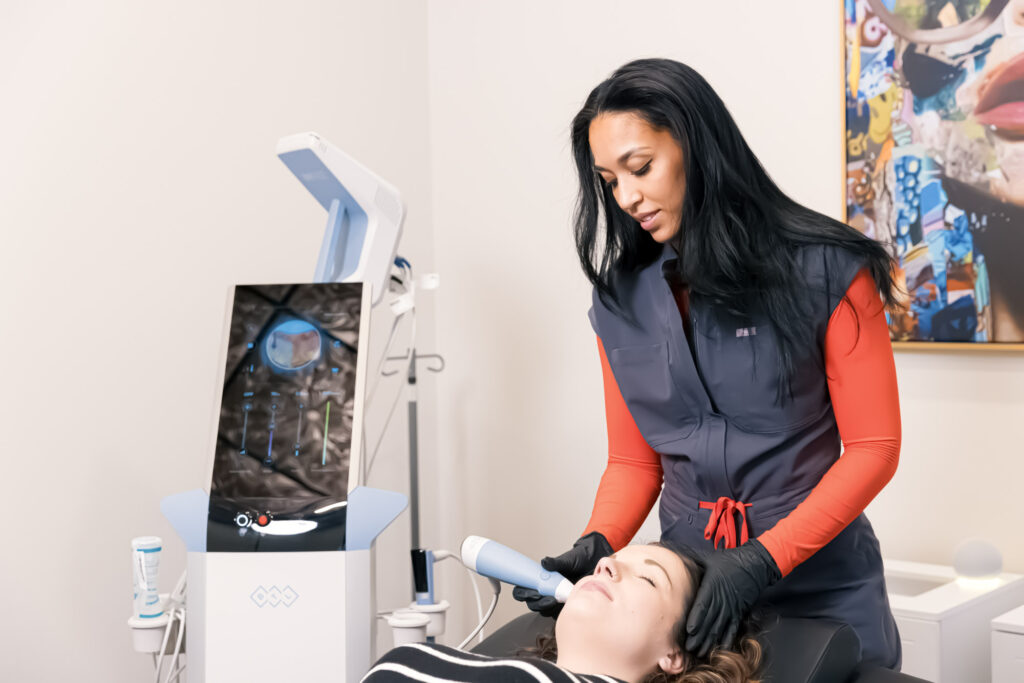 A female patient lays down on the treatment table while a provider uses RF microneedling for facials in Canton.